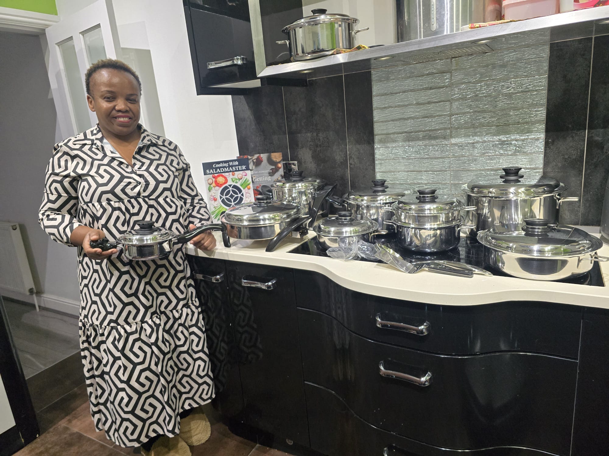 Happy customer at home with her full Saladmaster stainless steel cookware set and getting-started guides