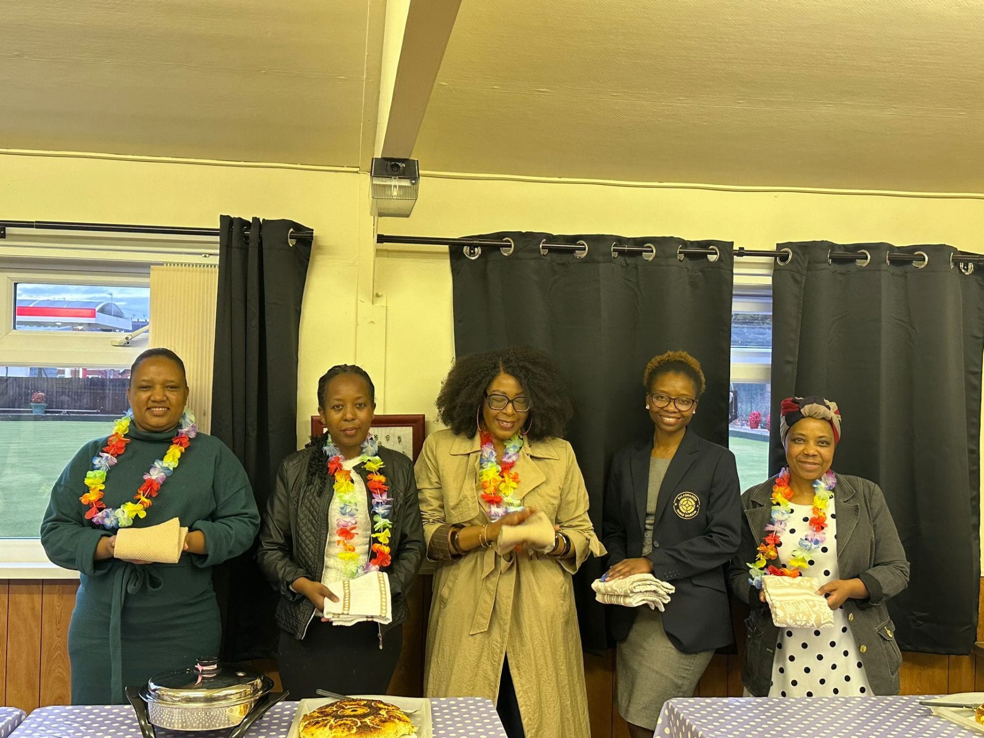 Guests at a Strength 2 Strength cooking school evening in Leicester wearing flower leis and holding Saladmaster kitchen textiles