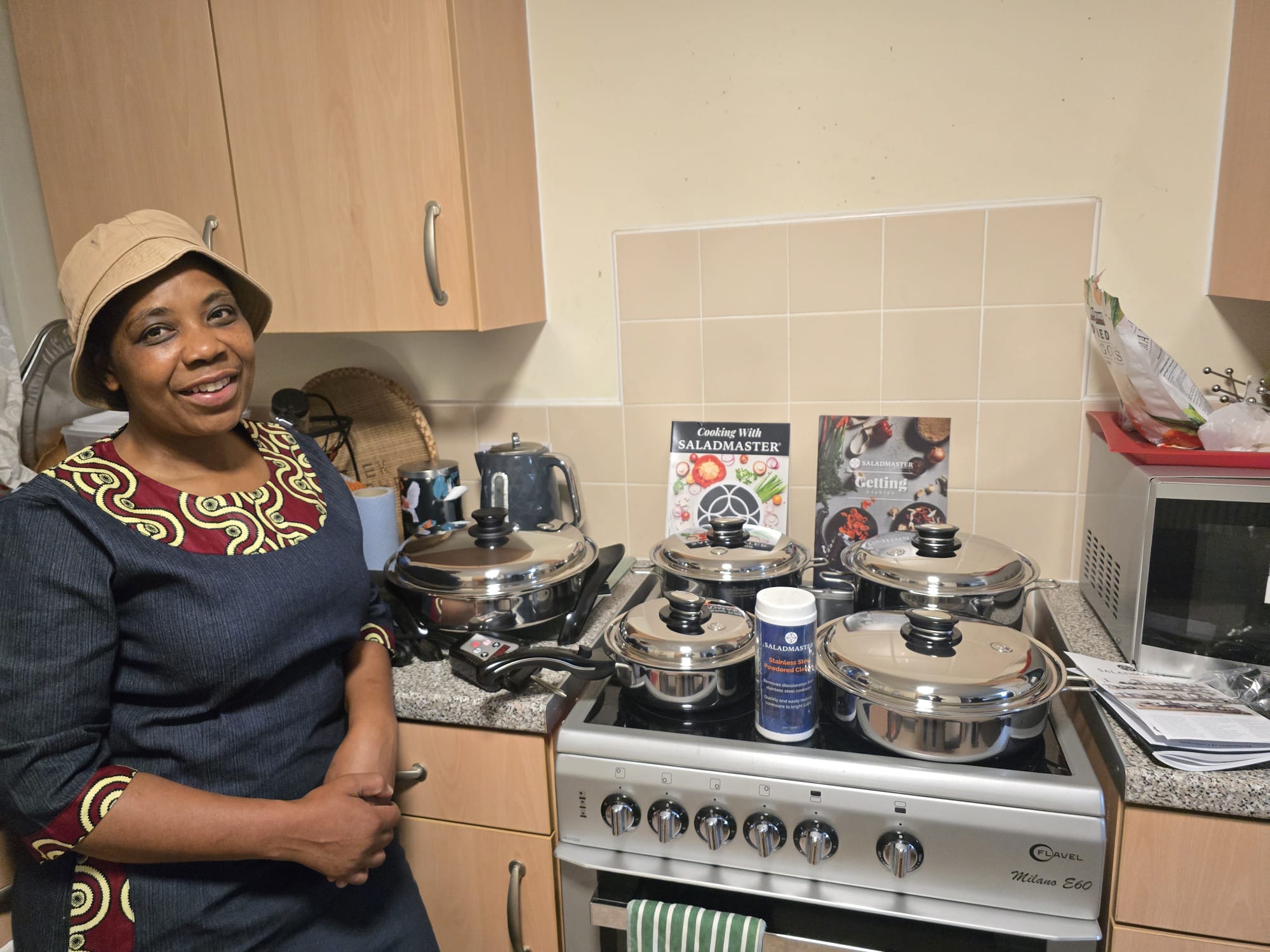 Smiling customer beside her full Saladmaster 316Ti stainless steel cookware collection at home