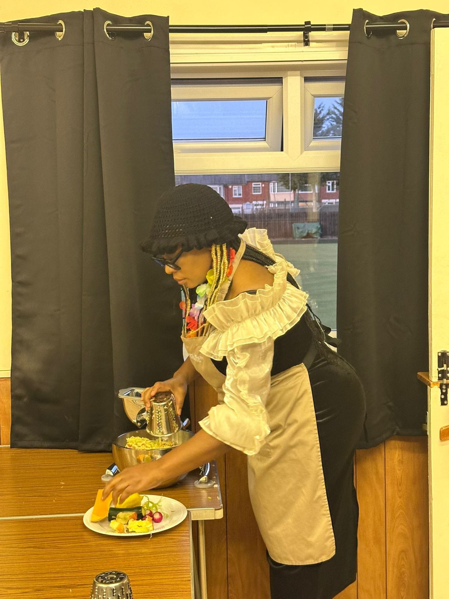 Guest in a Strength 2 Strength apron using the Saladmaster food processor to shred vegetables at a live demonstration