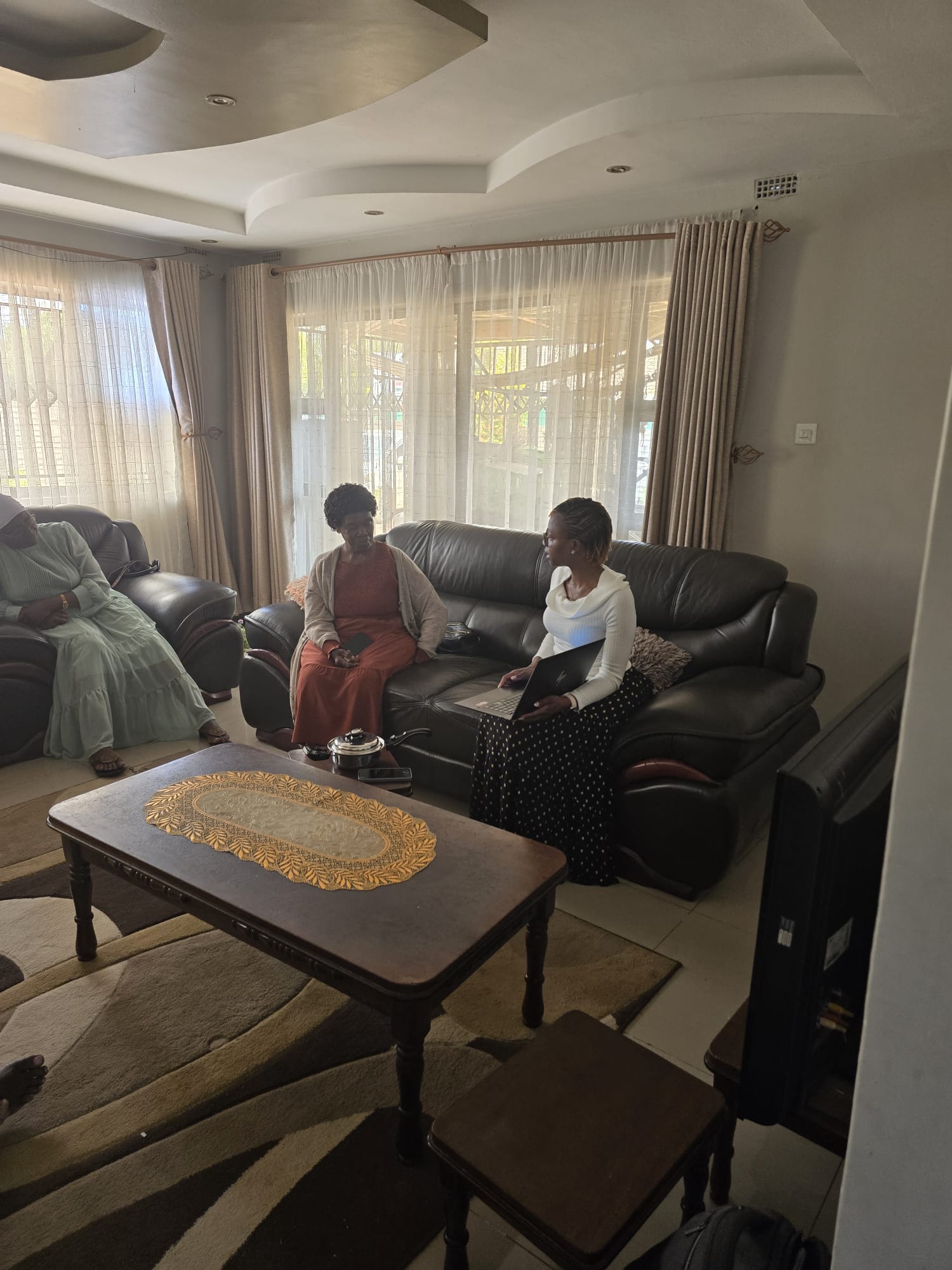 Consultant showing two guests a Saladmaster cooking presentation on a laptop in their family living room