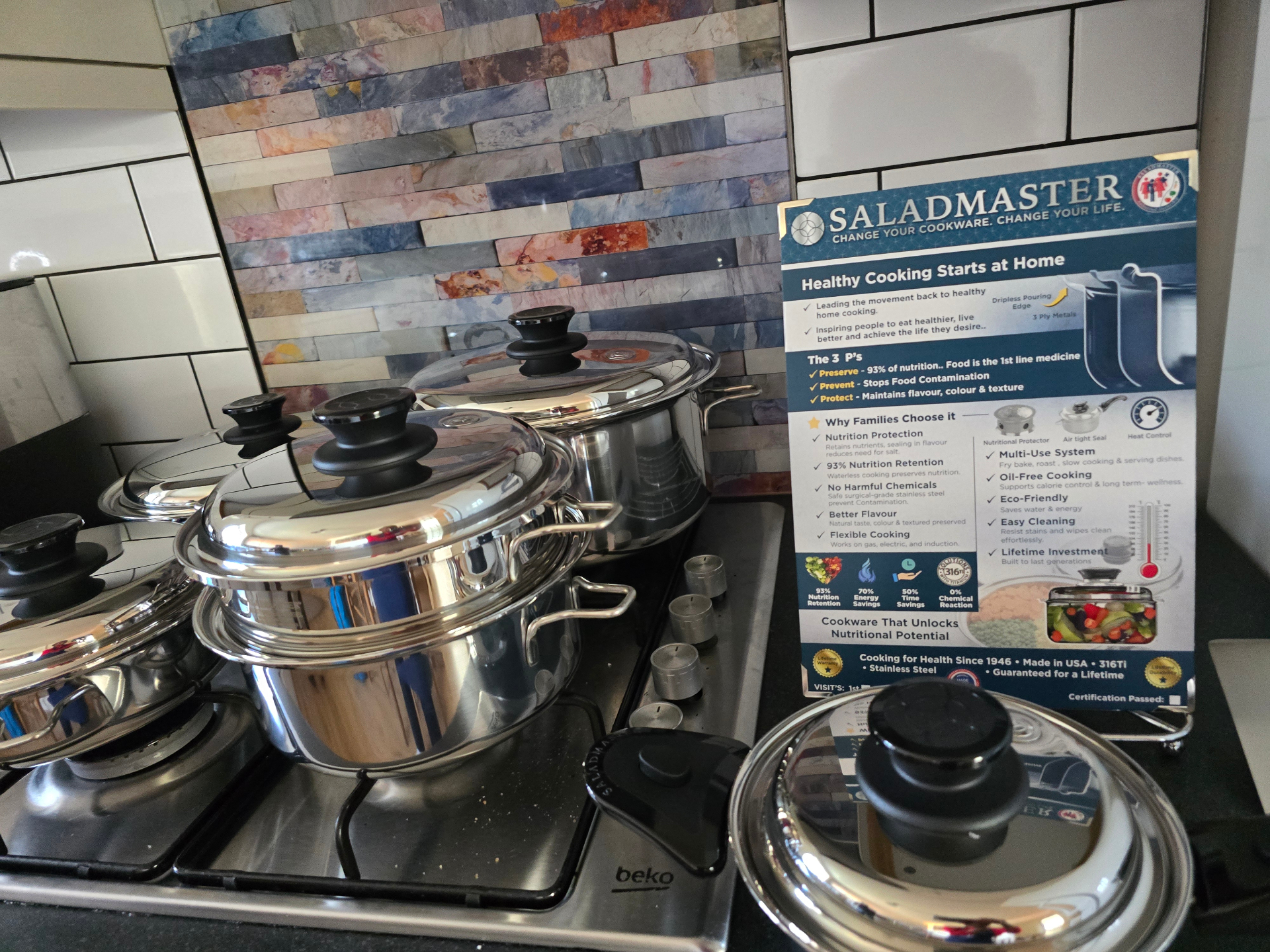 Saladmaster cookware on hob with healthy cooking poster