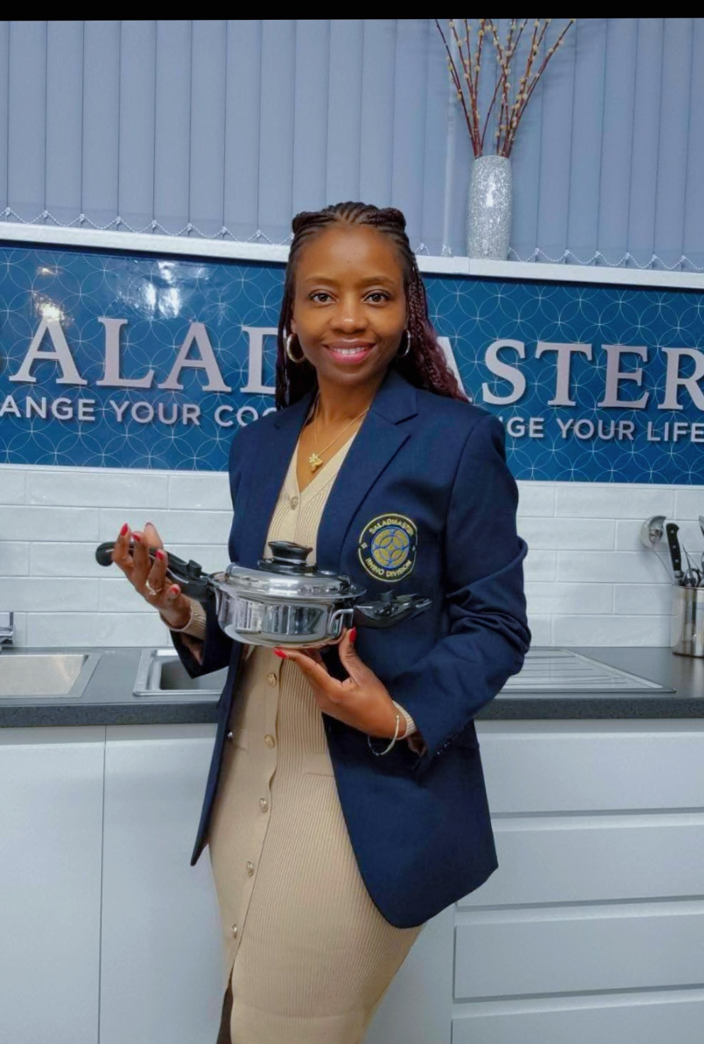 Authorised Saladmaster Dealer in a navy blazer holding Saladmaster stainless steel cookware in the Leeds studio