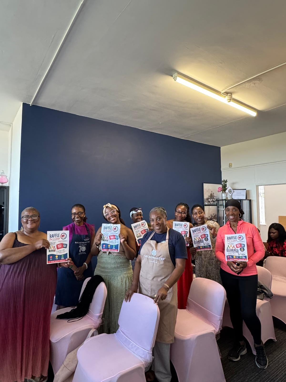 Community women holding Raffle for a Cause posters at a Strength 2 Strength unity in the community event