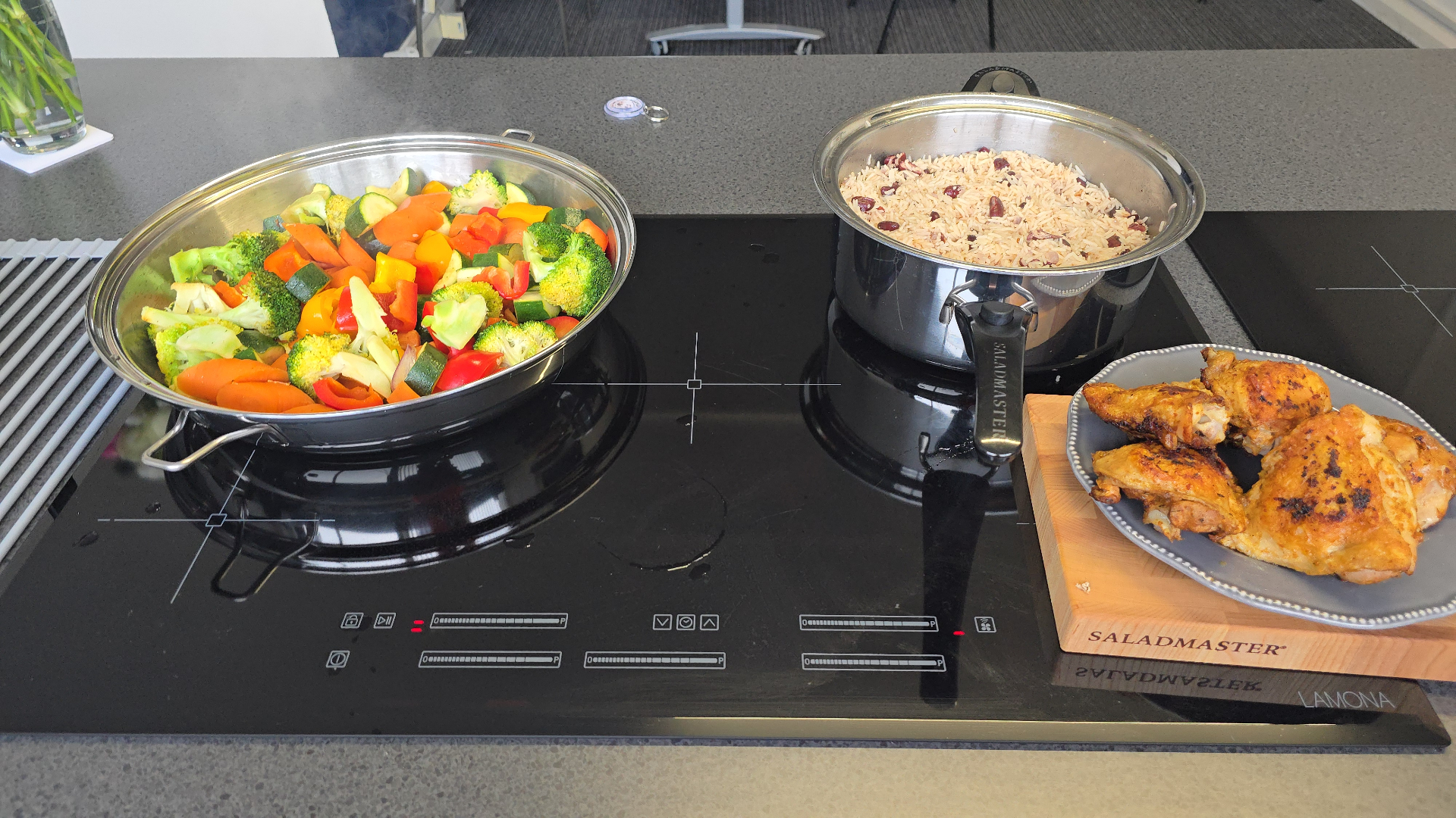 A Saladmaster cooktop spread with vegetables, rice and roast chicken